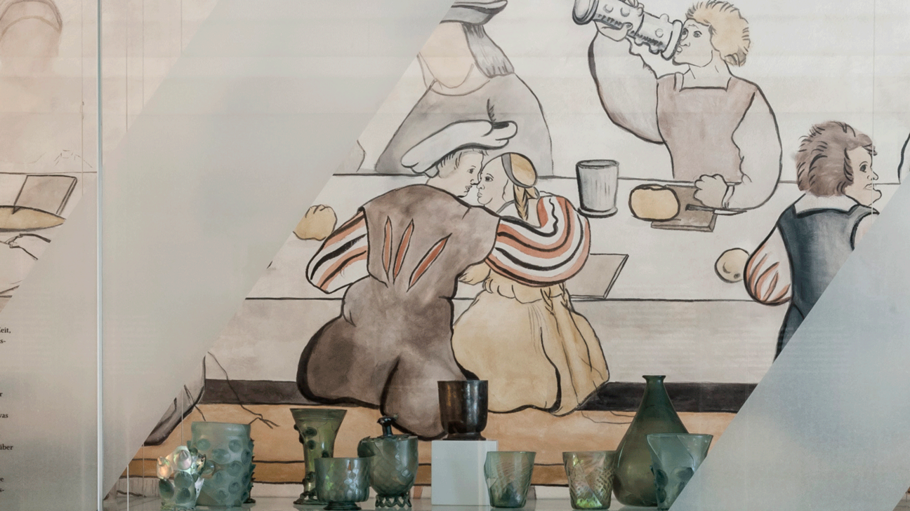 Nuppenbecher und ander Glasgefäße aufgereiht im Hintergrund das Bild der "Konstanzer Landknechthochzeit" das die Verwendung der Gläser zeigt.